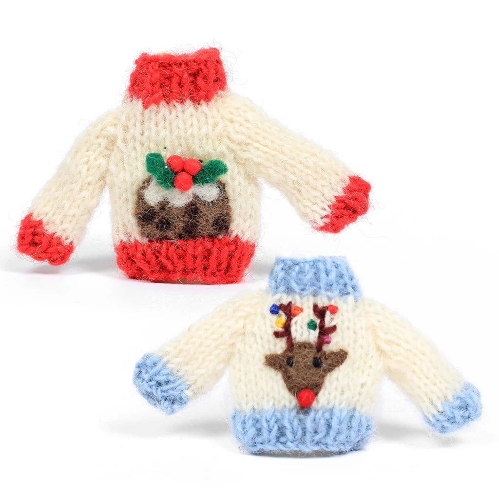 Two miniature knitted Christmas sweater accessories on a white background, one with a red knit collar and cuffs, a brown pudding with green holly, and a cream body, and the other with a light blue knit collar and cuffs, a brown reindeer face, and a cream body.