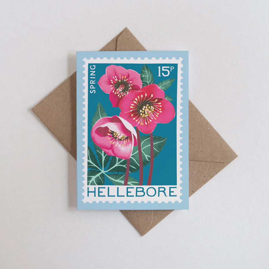 Card with a stamp design of pink hellebore flowers and a brown envelope on a light gray background