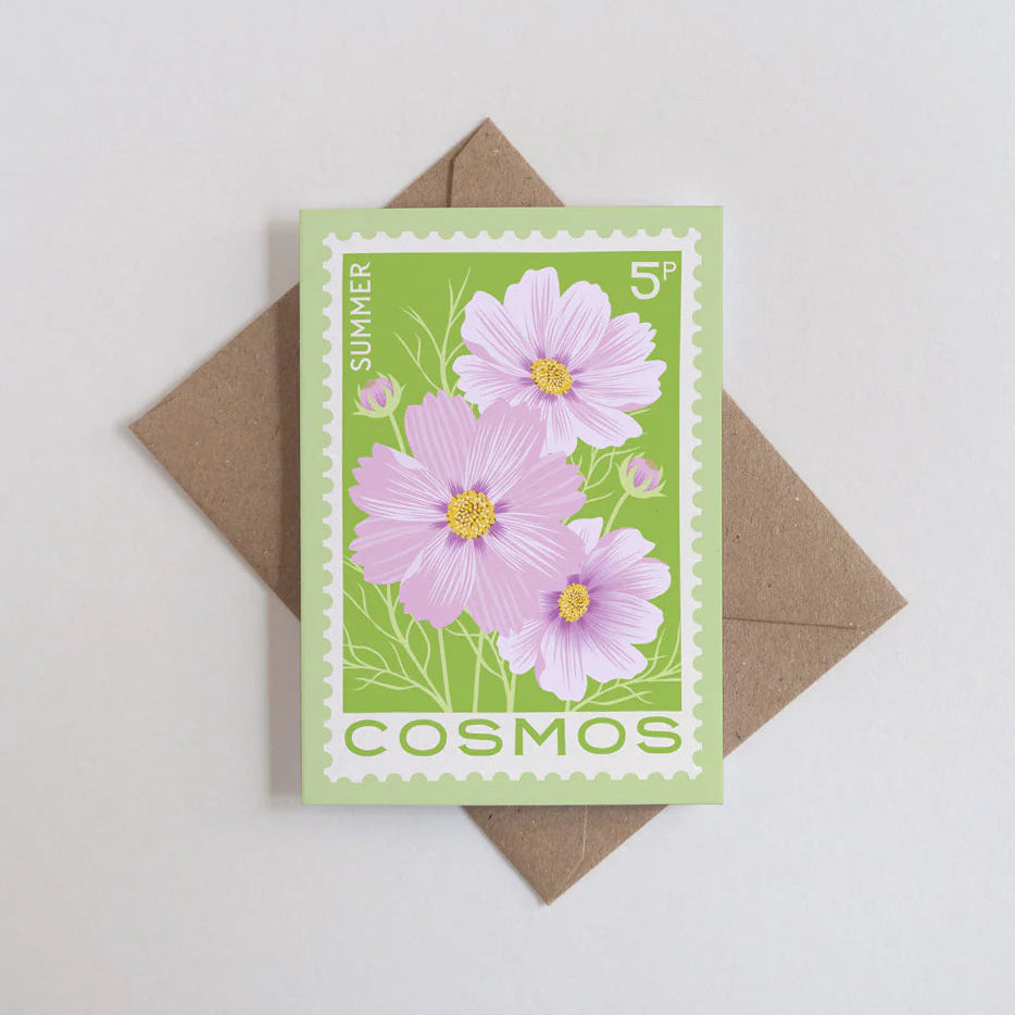 Card with pink cosmos flowers design and a brown envelope on a light gray background
