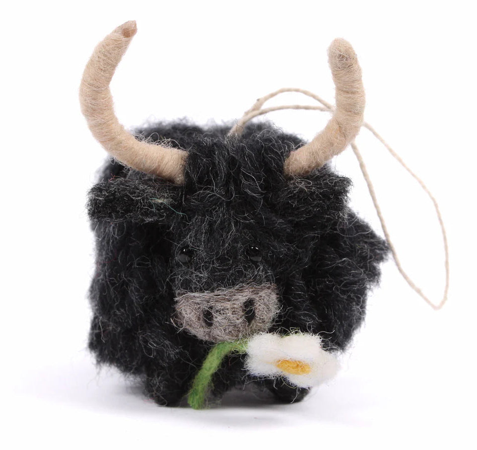 Felted toy highland cow with a flower on a white background