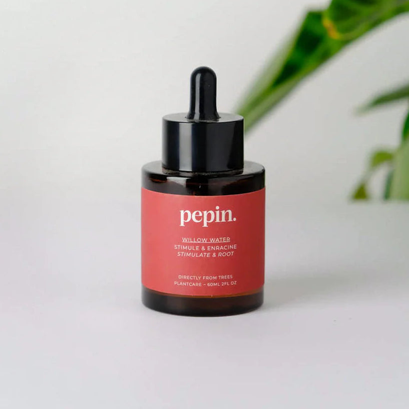Bottle of Pepin Willow Water with dropper on a white surface and a plant in the background