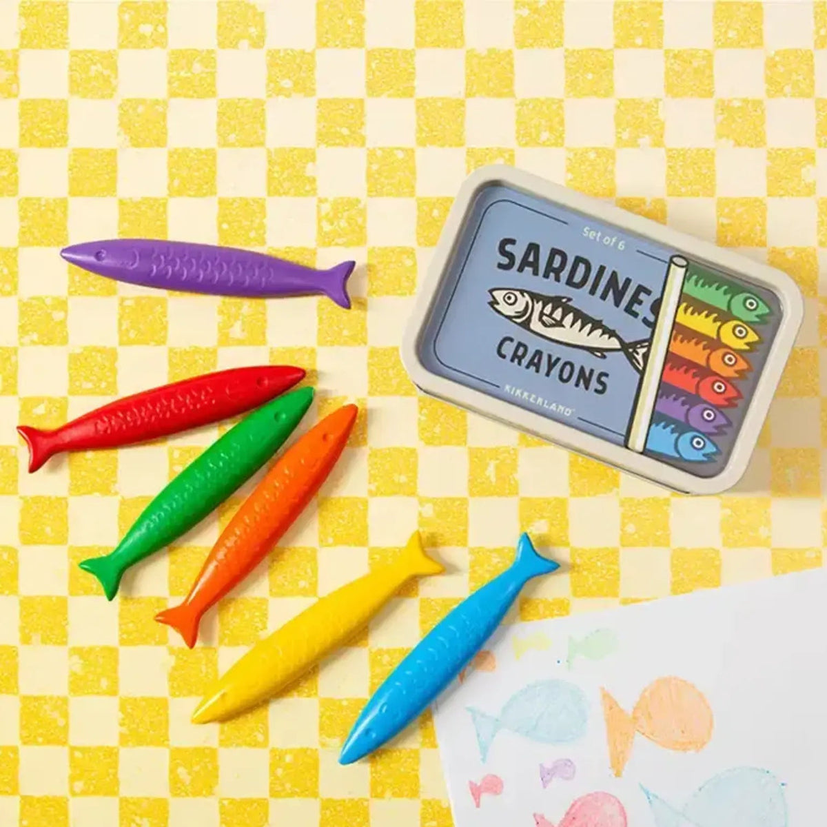 Colorful fish-shaped crayons and a box labeled 'Sardine Crayons' on a yellow checkered background.