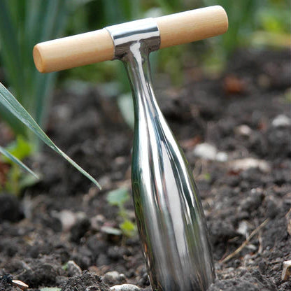 Metal dibber tool with wooden handle on soil