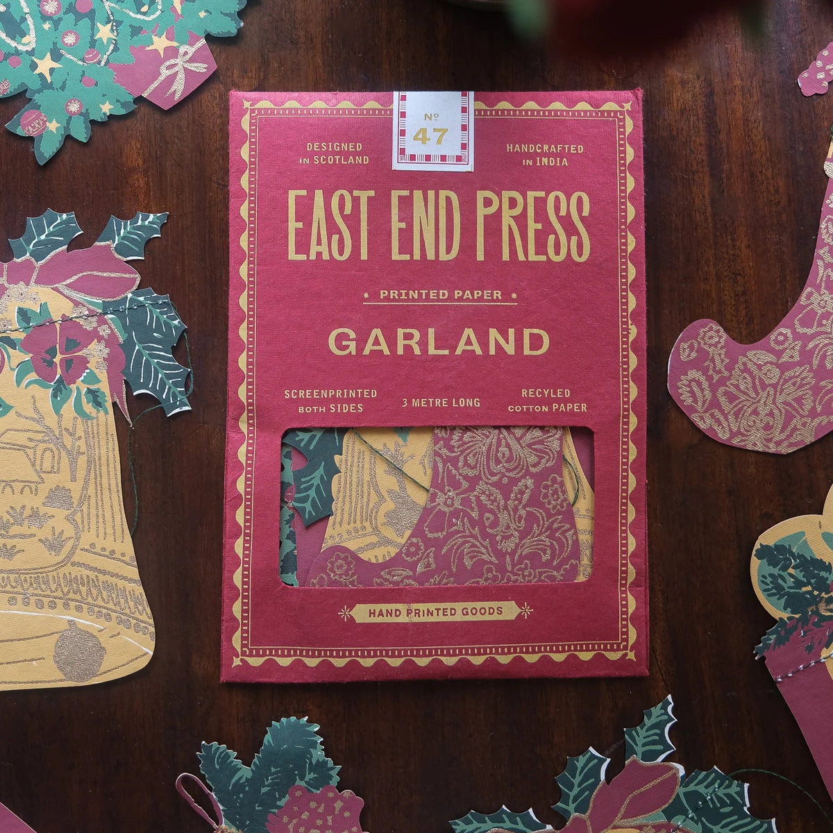 East End Press Garland packaging on a wooden surface with decorative paper pieces.