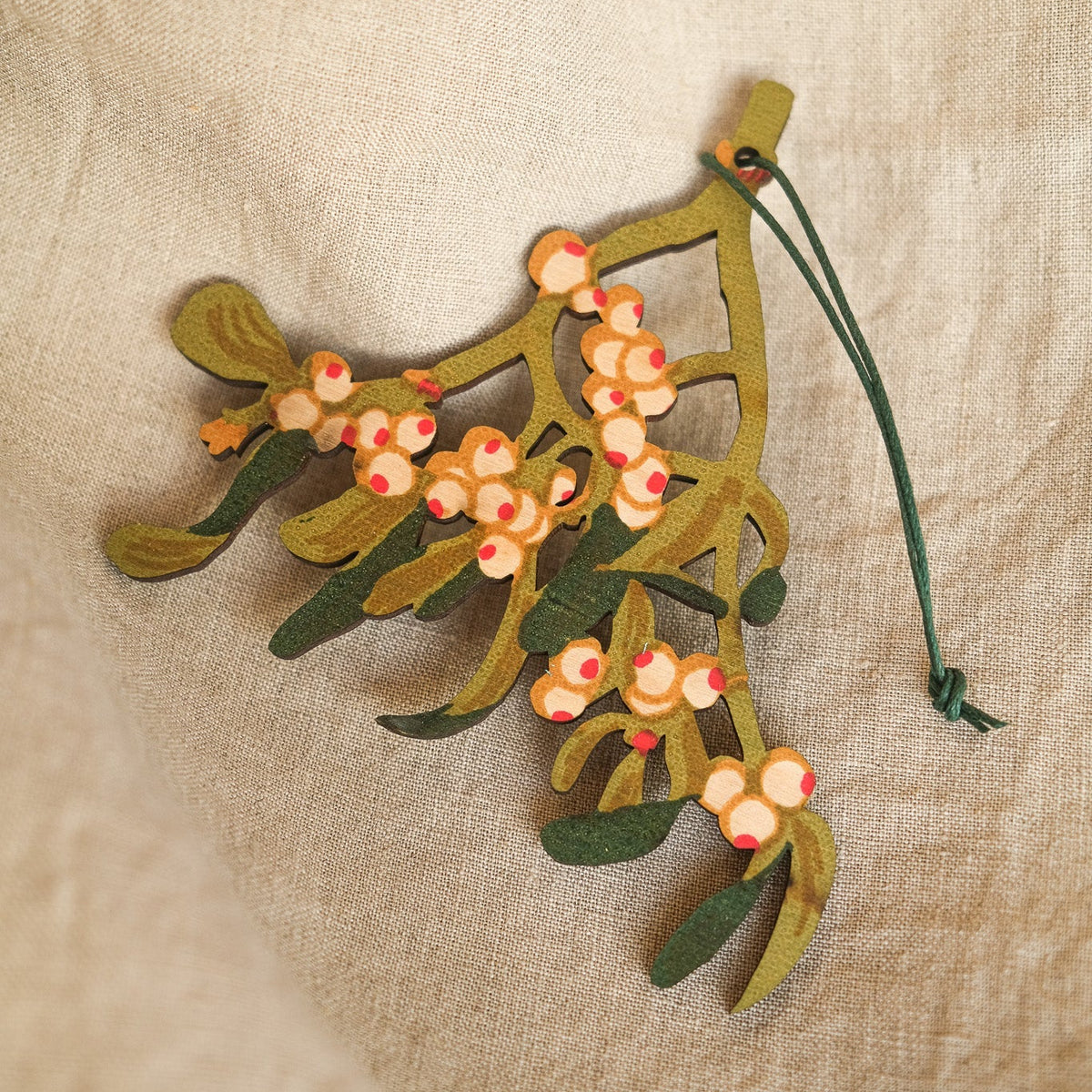 Decorative mistletoe ornament on a textured beige background