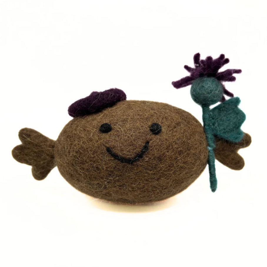 Felted brown Haggis with a purple hat and holding a thistle on a white background
