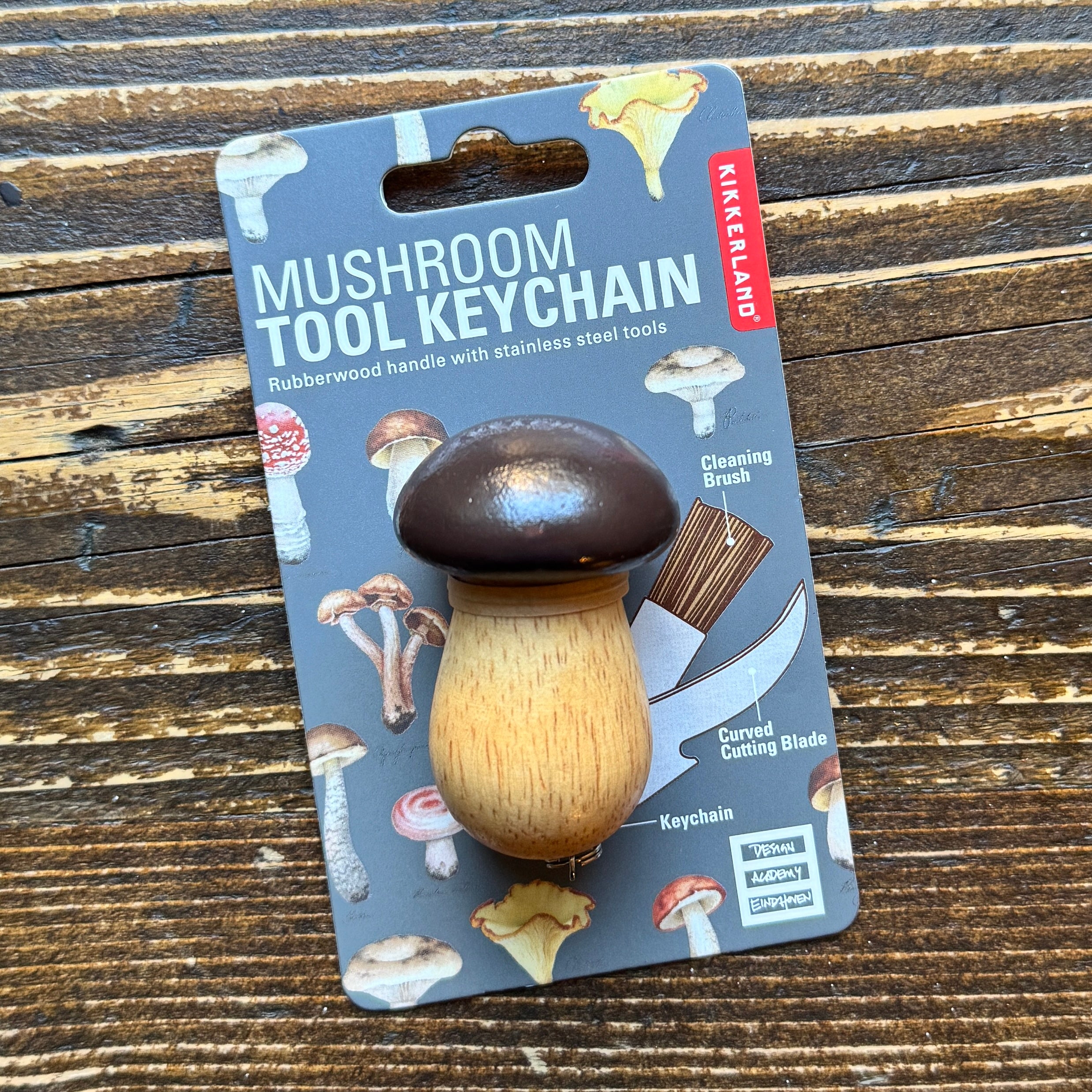 Mushroom tool keychain on a branded card with a wooden background