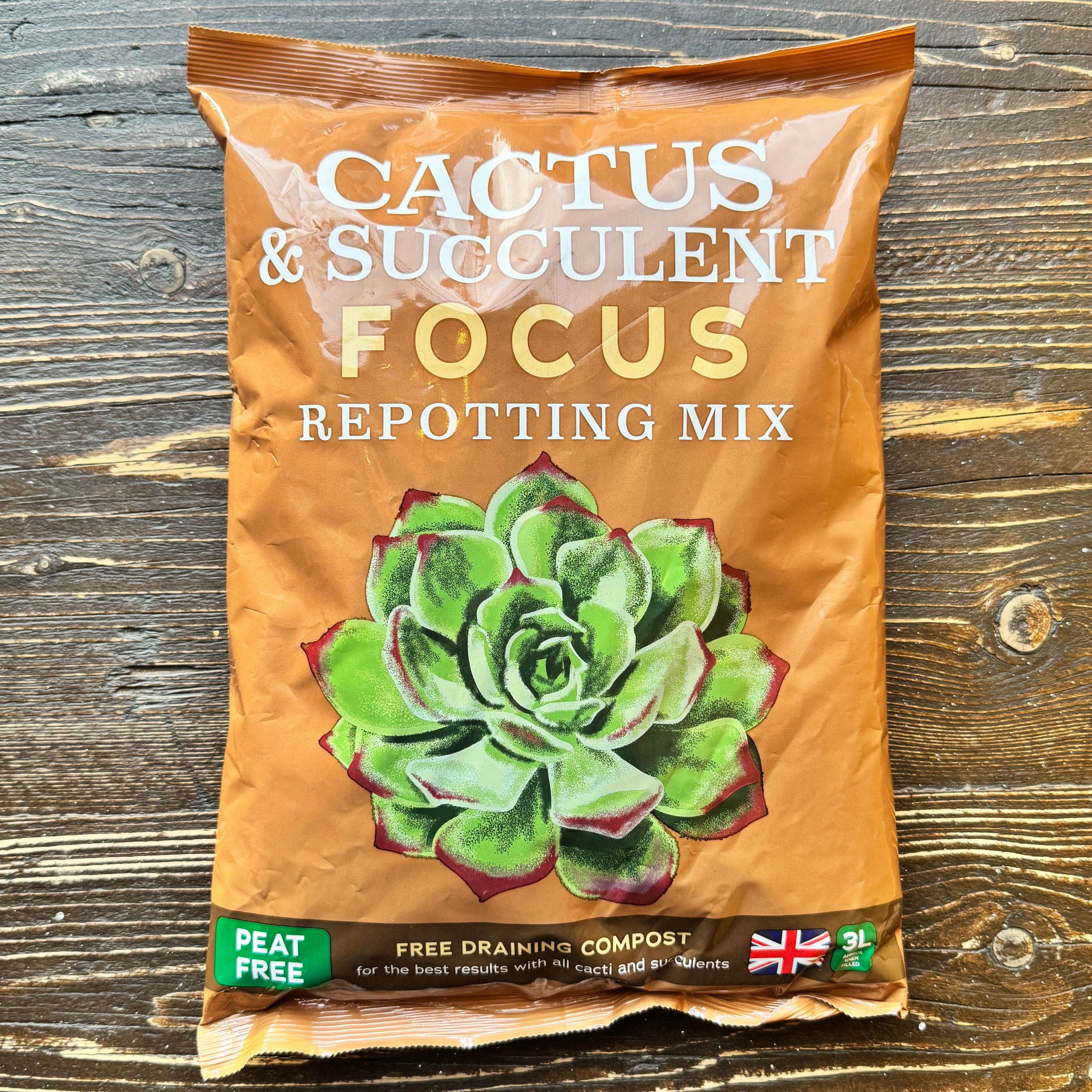 Bag of cactus and succulent repotting mix on a wooden surface