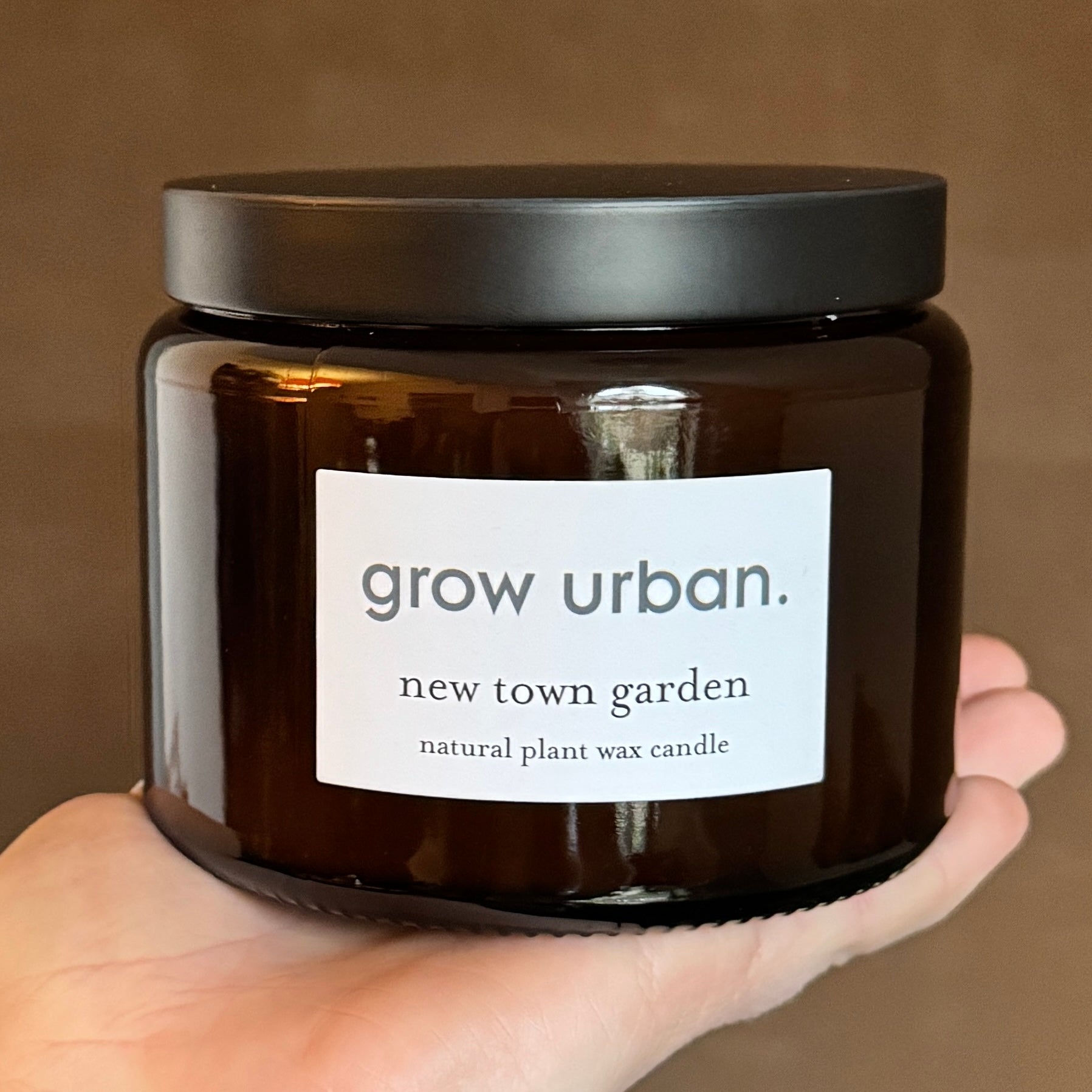 500ml New Town Garden candle by grow urban. in amber pharmacy glass with black lid, fresh citrus, pine and moss scent inspired by Edinburgh’s New Town.