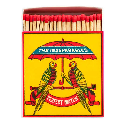 Matchbox with 'The Inseparables' design featuring two parrots under an umbrella.
